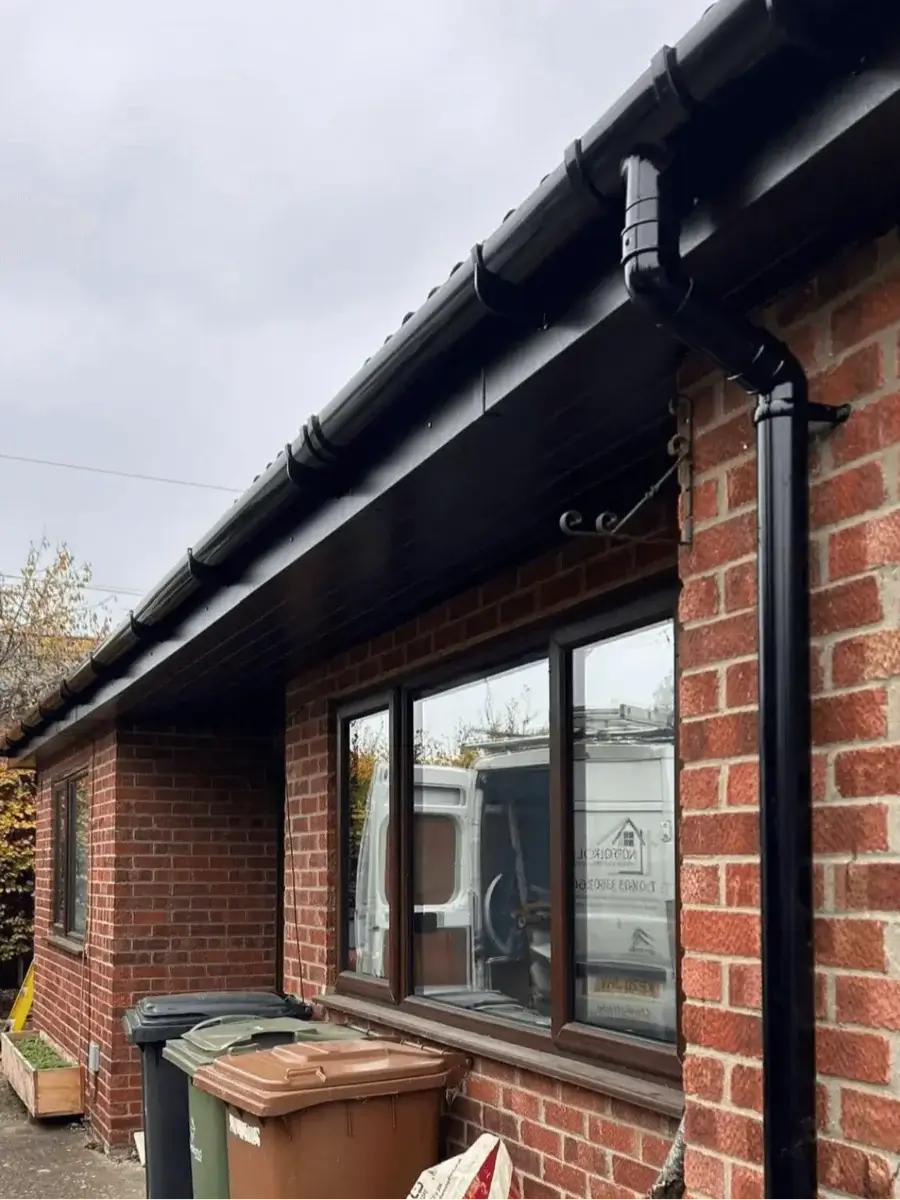Black Deepflow uPVC guttering system and matching downpipe neatly attached to a traditional red brick property by Norfolk Exterior Solutions